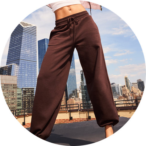 Woman standing posing in brown pants with a city background